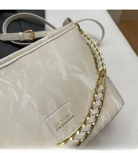 Detail showing the cream marble texture and golden metal chain strap of the bucket bag