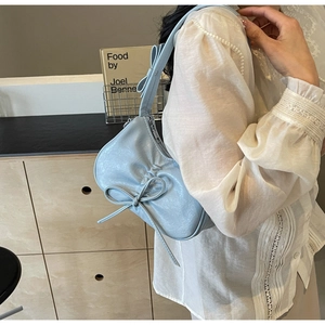 Detail of light blue pleated leather shoulder bag featuring a decorative front bow