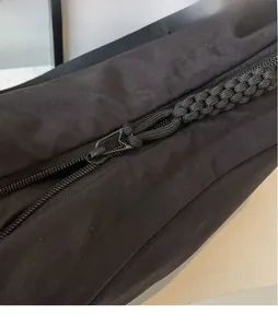 Detail of the smooth black metal zipper head and woven pull cord on nylon bag