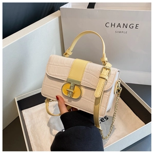 Close-up of beige crocodile pattern handbag with yellow leather strap and gold metal buckle