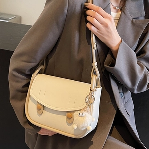 Chic off-white underarm saddle bag for women with decorative buttons and cute fur ball charm