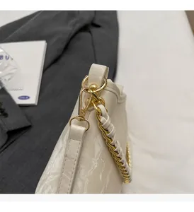 Close-up of the elegant cream white bucket bag featuring woven gold chain and leather strap
