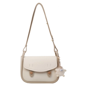 Minimalist beige faux leather underarm saddle bag with brown trim and plush charm