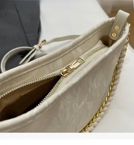 Macro detail of high-quality smooth metal zipper and gold chain on marble texture handbag