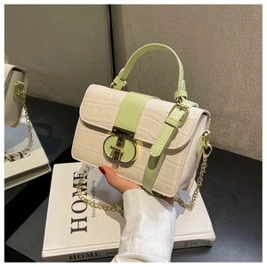 Detail showing white croc-embossed texture and mint green handles with gold metal chain