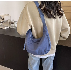 Blue nylon crossbody dumpling bag with woven zipper pull and adjustable wide strap