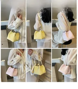 Detail view of mini pleated bucket bags in yellow and pink leather with thin straps