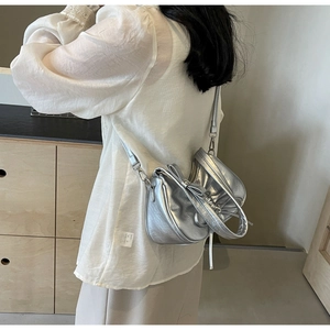 Detail of silver pleated crossbody bag with large bow handle and metallic finish