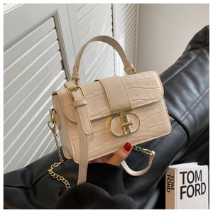 Detailed close-up of cream crocodile pattern bag with golden T-shaped geometric metal clasp