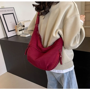 Detail of burgundy nylon hobo bag with side zipper pockets and woven puller on model