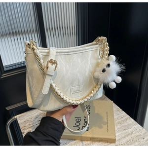 Detail of cream pleated bucket bag with metal chain strap and white plush doll charm