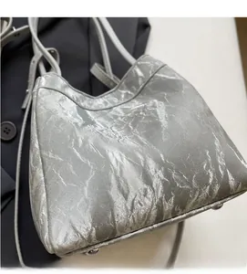 Detailed view of silver pleated handbag featuring metallic texture and protective feet