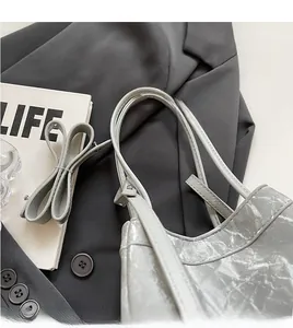 Detail of adjustable shoulder strap and crinkled texture on metallic silver bucket bag