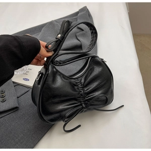 Detail of black pleated shoulder bag with a thin bow and silver metallic hardware