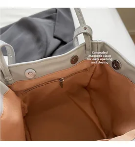 Detail view of mini grey handbag with orange fabric lining and magnetic snap buttons