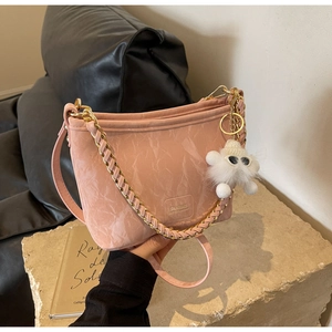 Close-up of pink pleated bucket bag featuring a gold chain and a white plush charm