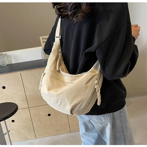 Detailed back view of a beige nylon crescent crossbody bag worn by a model