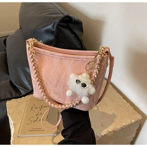Detail of pink marble textured bucket bag with gold chain strap and plush charm