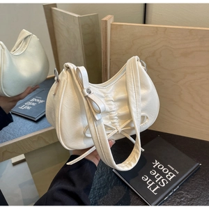 Detailed close-up of cream pleated crescent bag with side bow and zipper closure