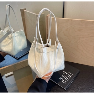 Detail of cream leather bucket bag with wrinkled texture and dual slim shoulder straps