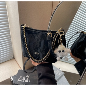 Detail of black pleated shoulder bag with gold chain and white plush charm accessory