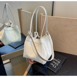 Close-up of cream-white bucket bag featuring soft crinkled texture and slim shoulder strap
