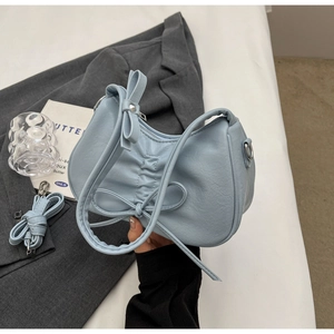Macro shot of light blue ruched leather handbag with a delicate bow and metal D-rings