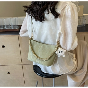 Detail of light green bucket bag with gold chain strap and cute plush charm pendant
