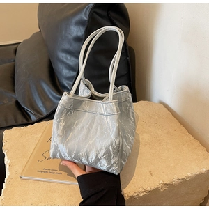 Detail of silver metallic wrinkled bucket bag featuring dual slim handles and foil texture