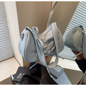 Close-up of light blue pleated croissant bag featuring a bow detail and silver zipper