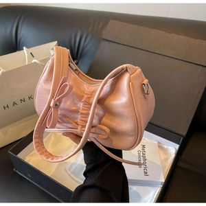 Detailed view of pink pleated underarm bag with bow decoration in a gift box setup