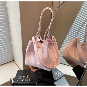 Detail of light pink pleated bucket bag with dual handles and wide shoulder strap