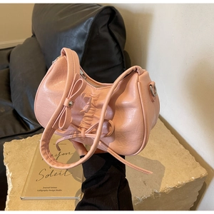 Detail of pink ruched underarm bag with bow decoration and smooth metal zipper closure