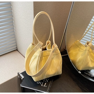 Detail of yellow tote bag with washed crinkle texture and silver buckle shown in mirror