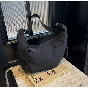 Close-up of a black nylon crescent bag with adjustable strap and woven zipper detail