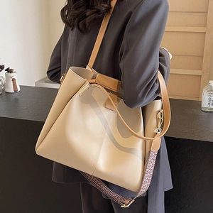 Minimalist beige PU leather tote bag with wide geometric strap worn by a model