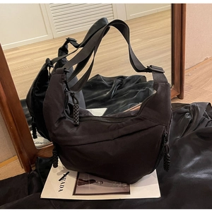 Detailed view of black nylon hobo bag featuring woven rope zipper pulls and a wide strap