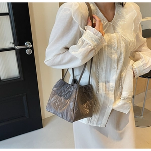 Detail view of dark grey bucket bag with pleated texture and thin shoulder straps