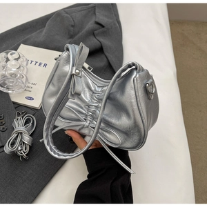 Detailed view of silver metallic pleated handbag with adjustable long shoulder strap