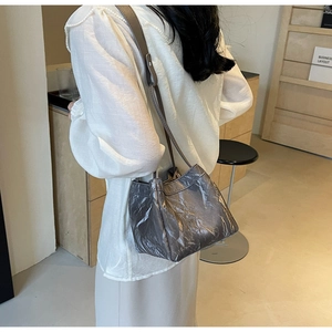 Detail of dark grey metallic bucket bag with stylish pleated texture and leather strap