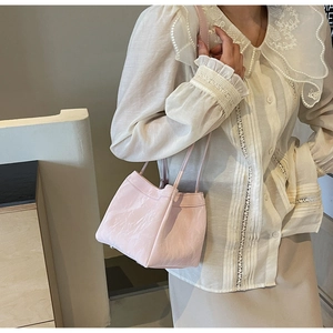 Detail of light pink pleated leather texture and slim straps on women's shoulder bag