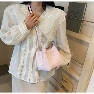 Macro detail of a light pink leather bucket bag with marble texture and thin shoulder strap