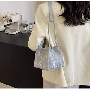 Detail of metallic wrinkled texture on light blue crossbody bucket bag shown on shoulder
