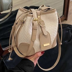 Chic woven straw bucket bag with brown leather trim and adjustable shoulder strap