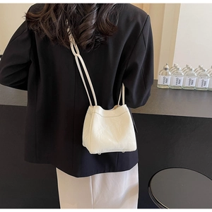Detail of cream pleated leather bucket bag with metallic studs and dual shoulder straps