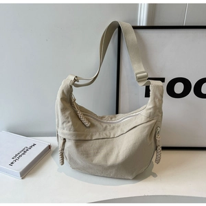 Detailed view of beige crescent nylon bag featuring adjustable strap and woven zipper pull
