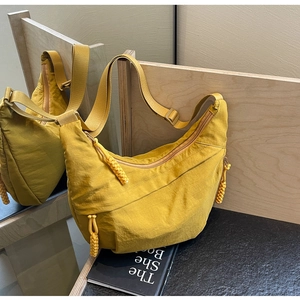Detail of yellow nylon crescent bag with woven knot zipper and soft matte texture