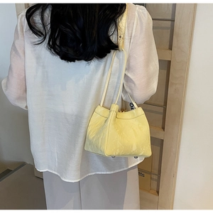 Mini yellow bucket bag with marble texture and printed wide strap worn by a model