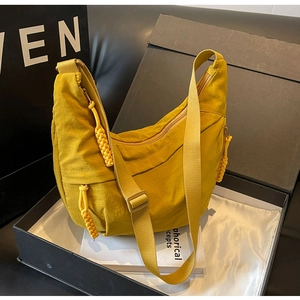 Macro shot of mustard yellow nylon dumpling bag with adjustable strap in luxury box