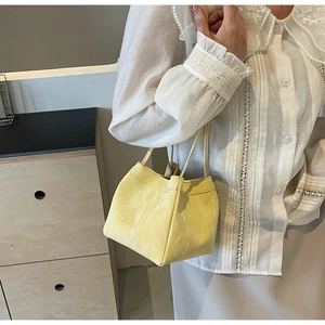Close-up of a pale yellow bucket bag with marble texture leather and thin double straps